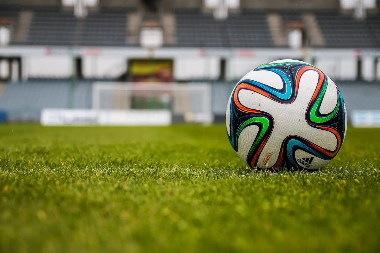Fodbold med mål og tribune i baggrunden